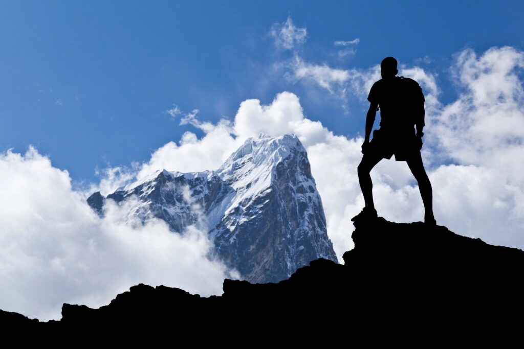 Silhouette of hiker on a mountain peak.